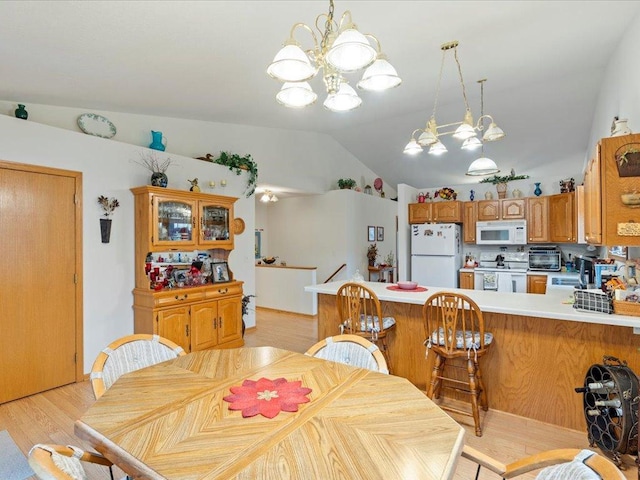 dining area with a notable chandelier, sink, light hardwood / wood-style flooring, and vaulted ceiling