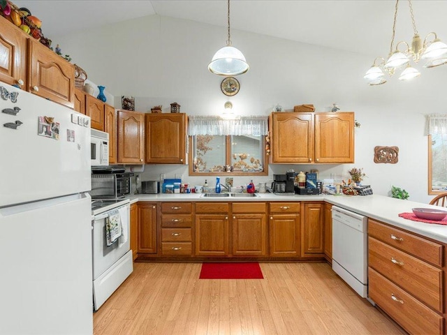 kitchen with pendant lighting, white appliances, lofted ceiling, sink, and a notable chandelier