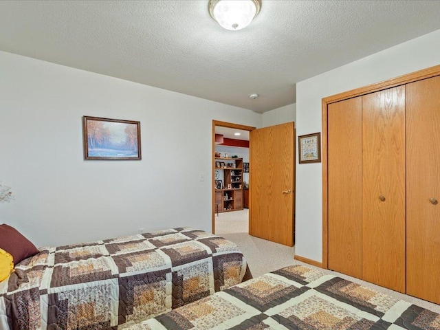 carpeted bedroom with a textured ceiling and a closet