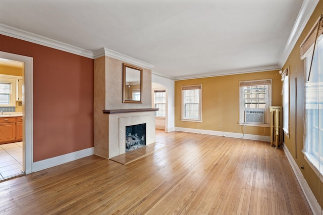 unfurnished living room with cooling unit, crown molding, a high end fireplace, and light hardwood / wood-style flooring