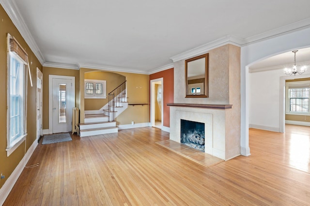 unfurnished living room featuring a fireplace, hardwood / wood-style flooring, an inviting chandelier, and crown molding