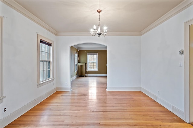 unfurnished dining area featuring a chandelier, light wood-type flooring, and crown molding