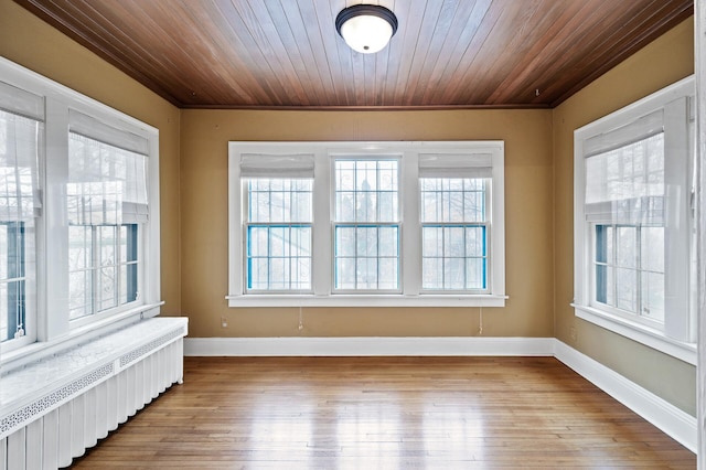 unfurnished sunroom featuring radiator, a healthy amount of sunlight, and wood ceiling