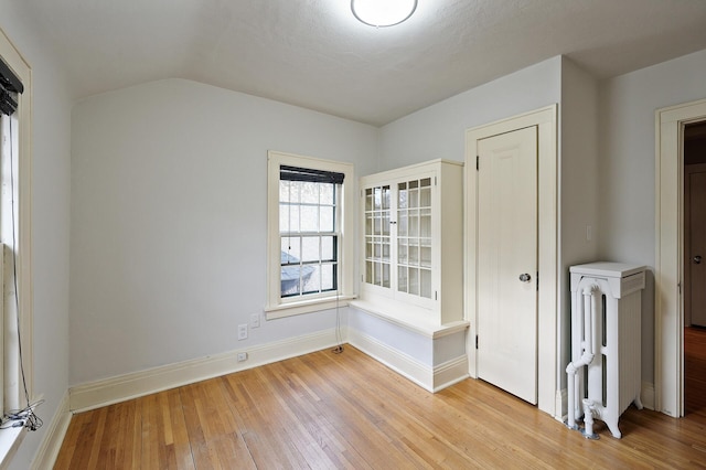 empty room with radiator heating unit, a textured ceiling, and light wood-type flooring