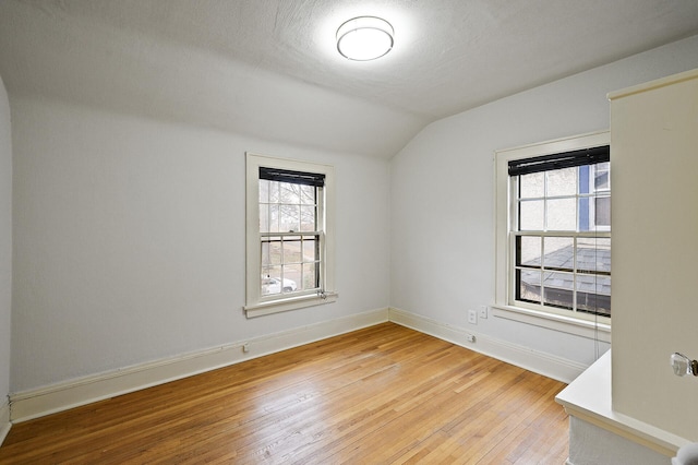 empty room featuring light hardwood / wood-style floors, lofted ceiling, and a textured ceiling