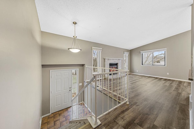 foyer with a textured ceiling, dark hardwood / wood-style flooring, lofted ceiling, and a fireplace