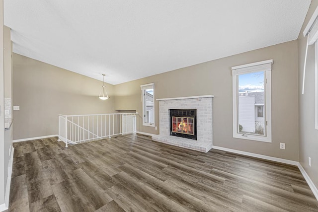 unfurnished living room with wood-type flooring and a brick fireplace