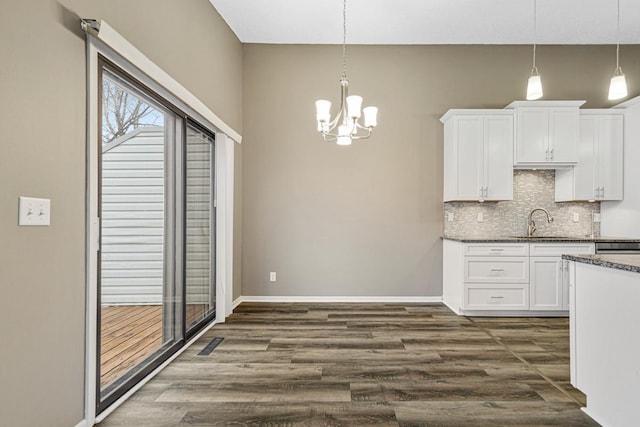 kitchen featuring dark hardwood / wood-style flooring, white cabinets, and hanging light fixtures