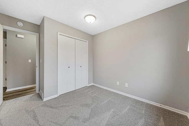 unfurnished bedroom with a textured ceiling, carpet floors, and a closet