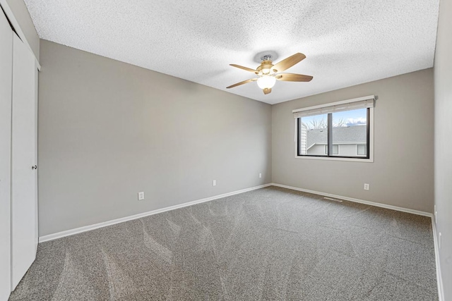 spare room featuring carpet flooring, ceiling fan, and a textured ceiling