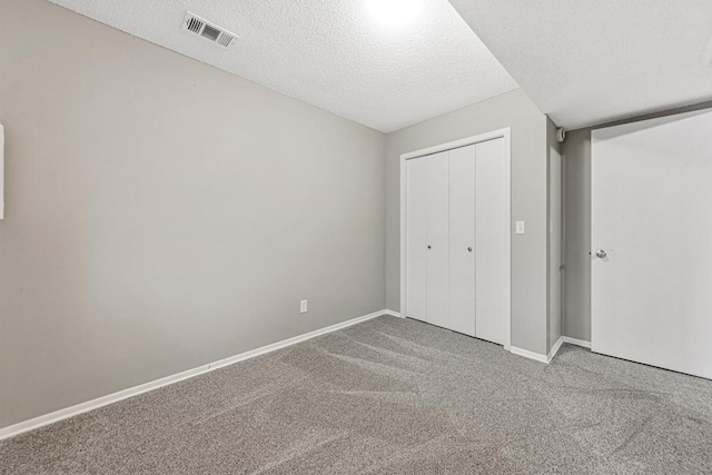 unfurnished bedroom featuring carpet floors, a textured ceiling, and a closet