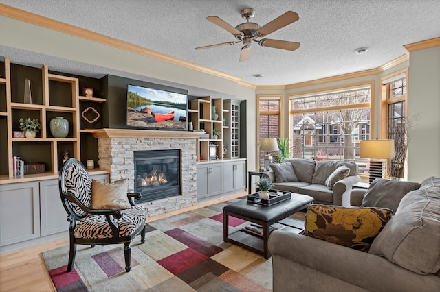 living room with a textured ceiling, ornamental molding, a fireplace, and ceiling fan
