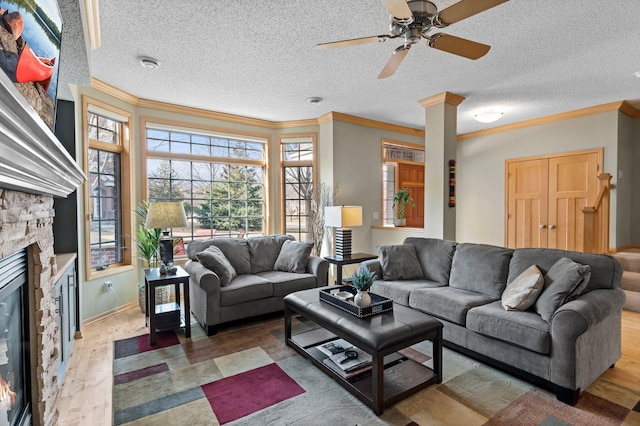 living room featuring crown molding, a textured ceiling, ceiling fan, and a fireplace