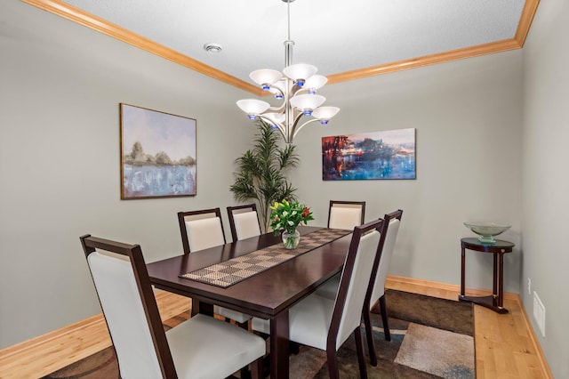 dining space with baseboards, a chandelier, ornamental molding, and wood finished floors
