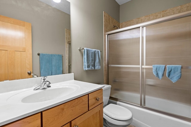 bathroom with vanity, enclosed tub / shower combo, and toilet