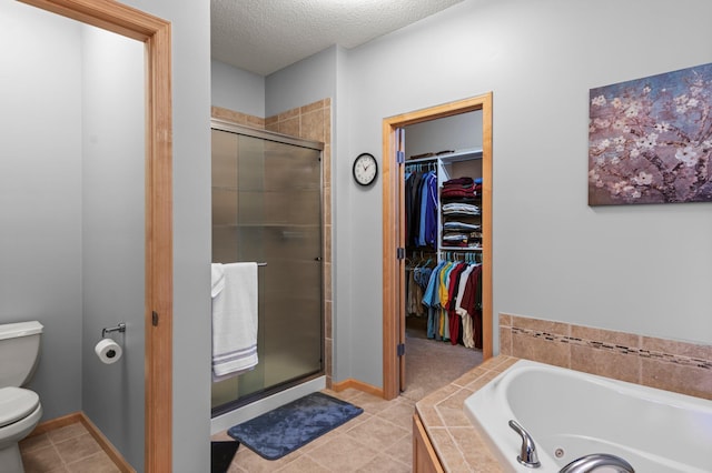 full bath with toilet, a textured ceiling, a tub with jets, a spacious closet, and a stall shower