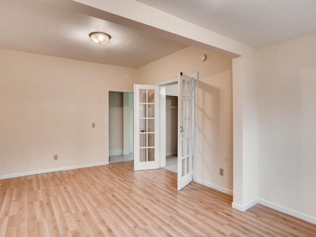 spare room with french doors and light hardwood / wood-style flooring