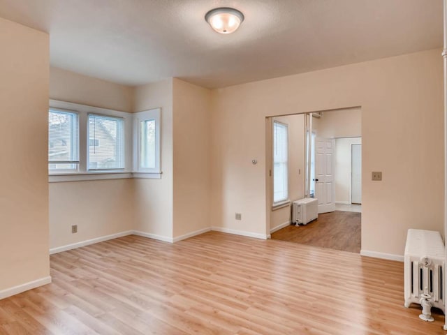 spare room with light hardwood / wood-style floors and radiator heating unit