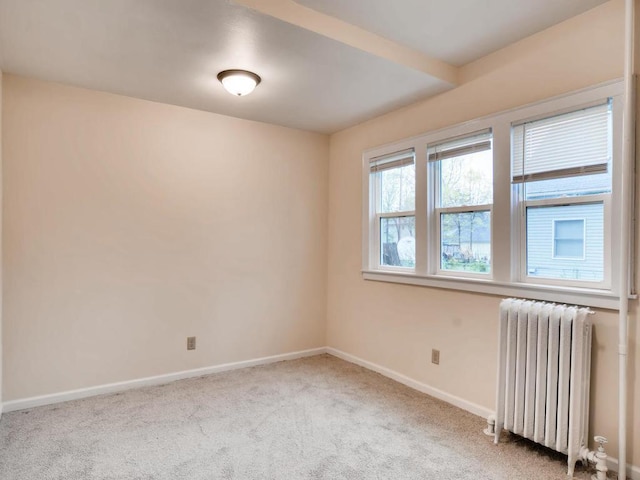 spare room featuring radiator heating unit and light colored carpet