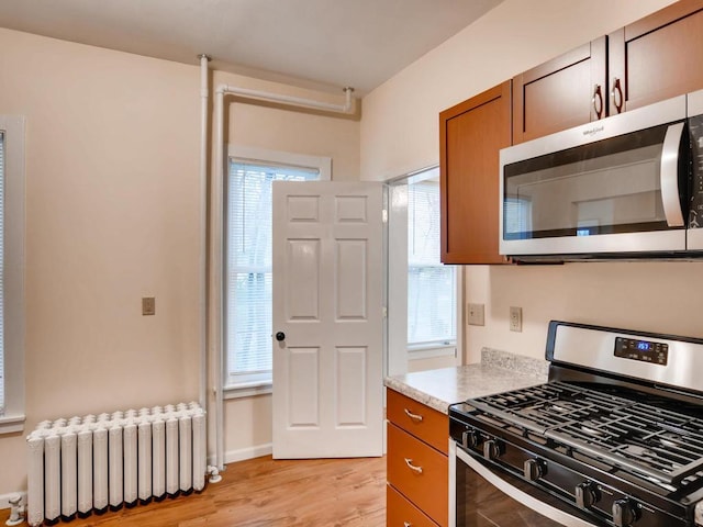 kitchen featuring appliances with stainless steel finishes, light hardwood / wood-style flooring, and radiator