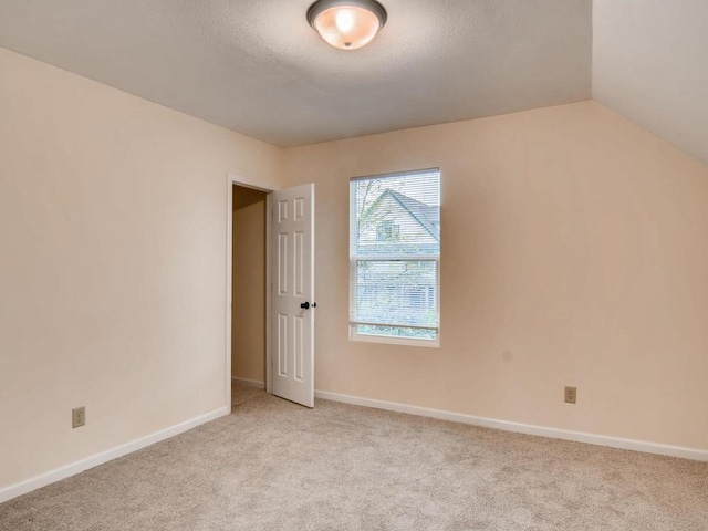 carpeted spare room with a textured ceiling and lofted ceiling