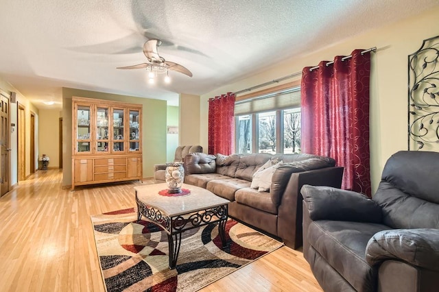 living room with ceiling fan, wood-type flooring, and a textured ceiling