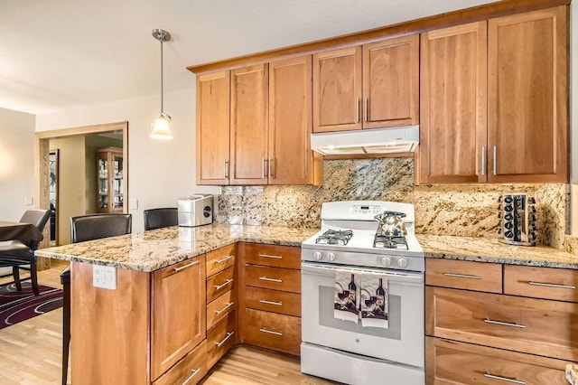 kitchen featuring light stone counters, decorative light fixtures, white gas range oven, and kitchen peninsula