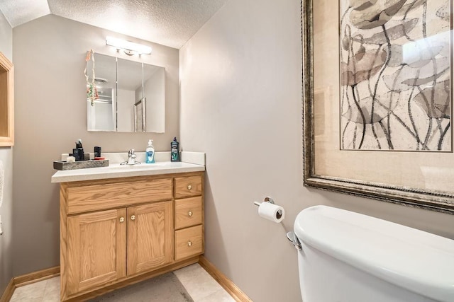 bathroom featuring tile patterned flooring, vanity, a textured ceiling, and toilet