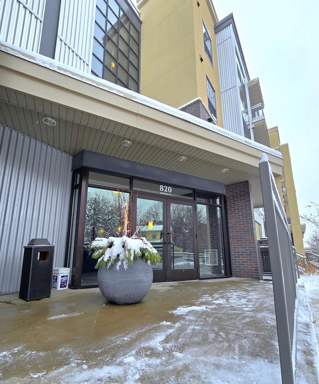 snow covered property entrance featuring french doors