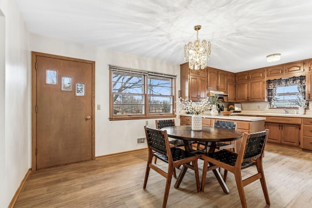 dining area featuring plenty of natural light, an inviting chandelier, and light wood-type flooring