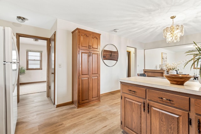 kitchen with light hardwood / wood-style flooring, an inviting chandelier, decorative light fixtures, and white refrigerator