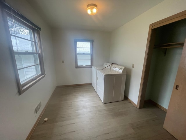 clothes washing area with washer and dryer and light hardwood / wood-style floors