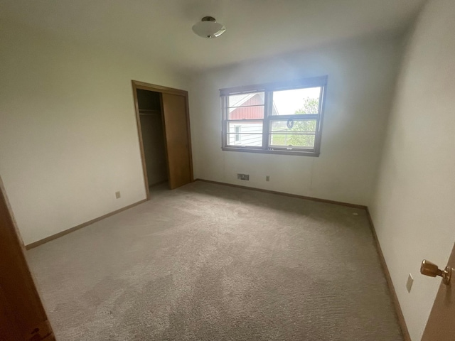 unfurnished bedroom with light carpet and a closet