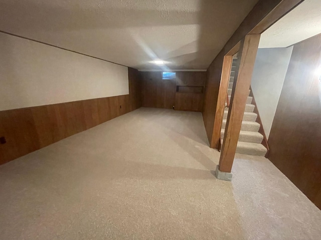 basement with wood walls, carpet floors, and a textured ceiling