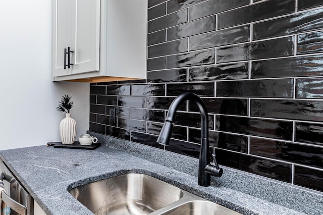 interior details featuring backsplash, stone countertops, white cabinetry, and sink