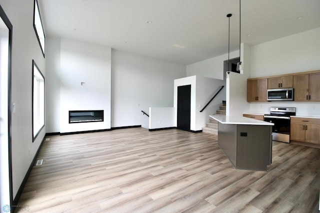 6721 67th Ave S, Horace, ND 58047 - kitchen featuring appliances with stainless steel finishes, light wood-type flooring, light countertops, a high ceiling, and open floor plan