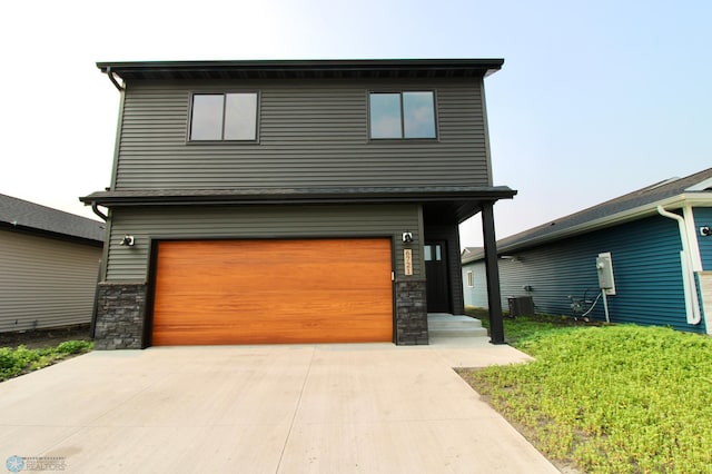 6721 67th Ave S, Horace, ND 58047 - view of front of house featuring a garage, concrete driveway, stone siding, and central AC unit