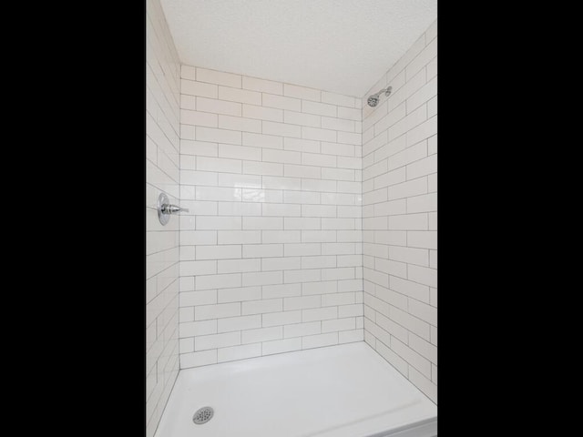 bathroom featuring a tile shower and a textured ceiling