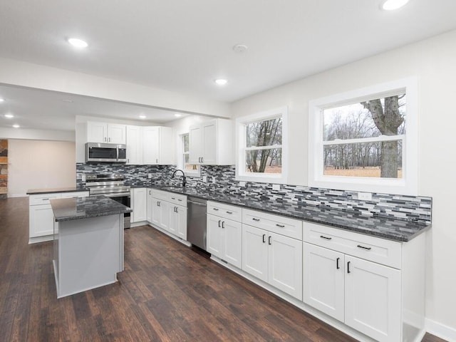 kitchen with backsplash, dark hardwood / wood-style floors, appliances with stainless steel finishes, a kitchen island, and white cabinetry