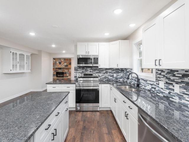 kitchen featuring tasteful backsplash, dark stone counters, stainless steel appliances, dark wood-type flooring, and white cabinetry