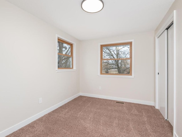 unfurnished bedroom featuring multiple windows, a closet, and carpet floors