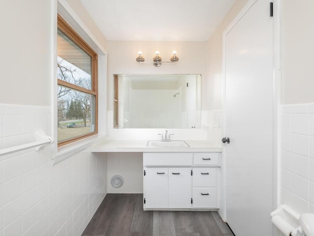 bathroom with hardwood / wood-style floors, vanity, and tile walls