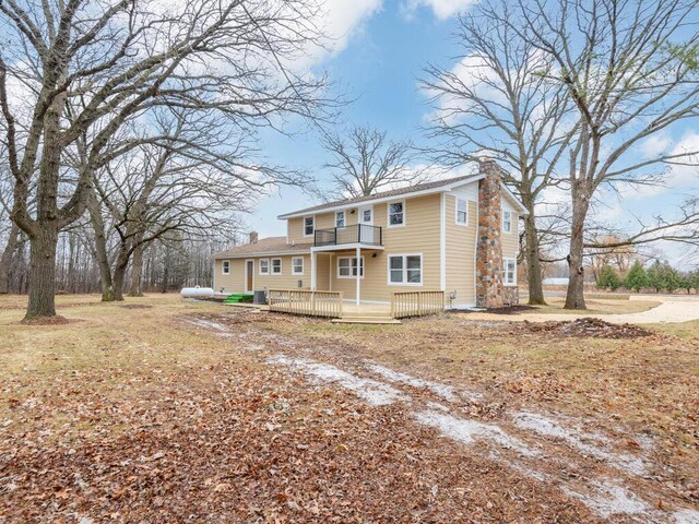 back of house featuring a lawn, a balcony, and a deck