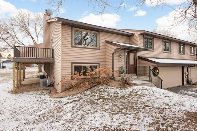 raised ranch featuring a balcony, a garage, and central air condition unit