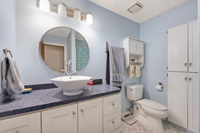 bathroom with vanity, a textured ceiling, and toilet