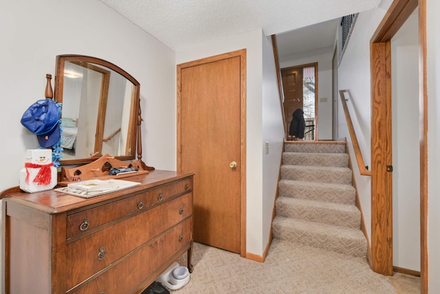 hallway with light carpet and a textured ceiling