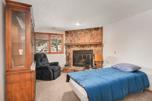 bedroom featuring a fireplace, carpet, and a textured ceiling