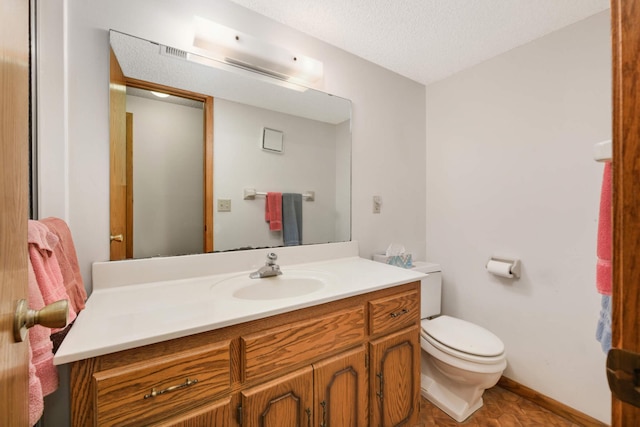 bathroom with vanity, toilet, and a textured ceiling