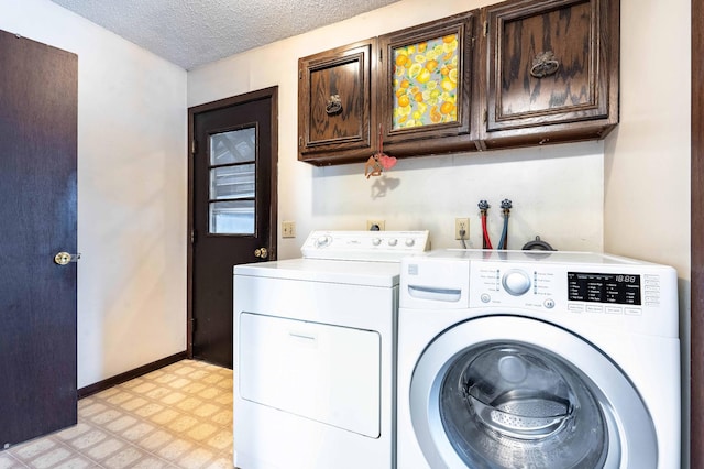 clothes washing area featuring washer and clothes dryer, cabinets, and a textured ceiling