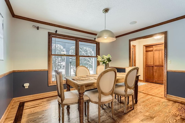 dining space featuring crown molding, light hardwood / wood-style flooring, and a textured ceiling